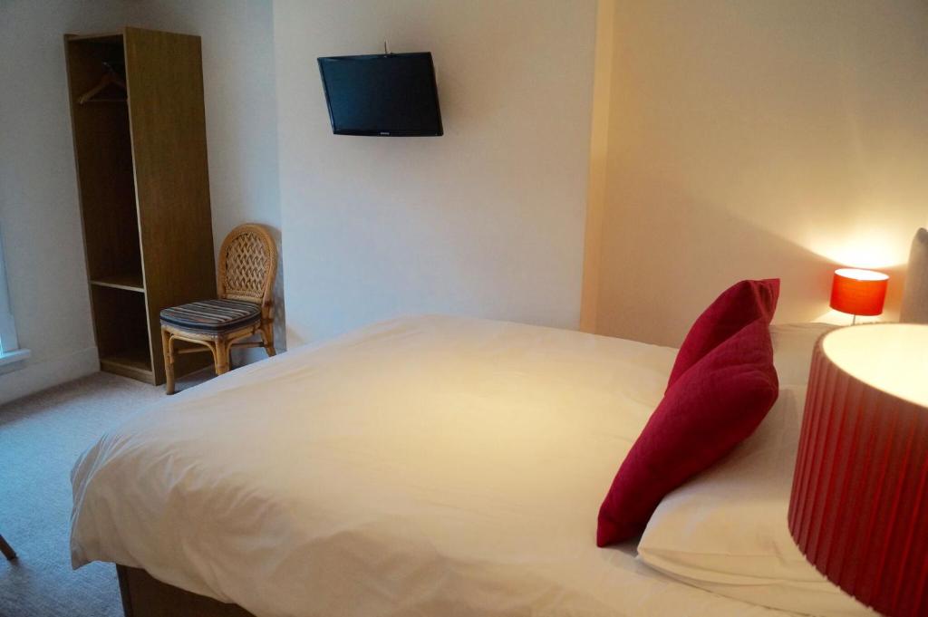 a bedroom with a white bed with red pillows at The Arun View Inn in Littlehampton
