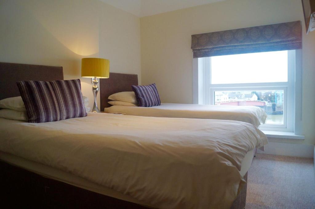 two beds in a hotel room with a window at The Arun View Inn in Littlehampton