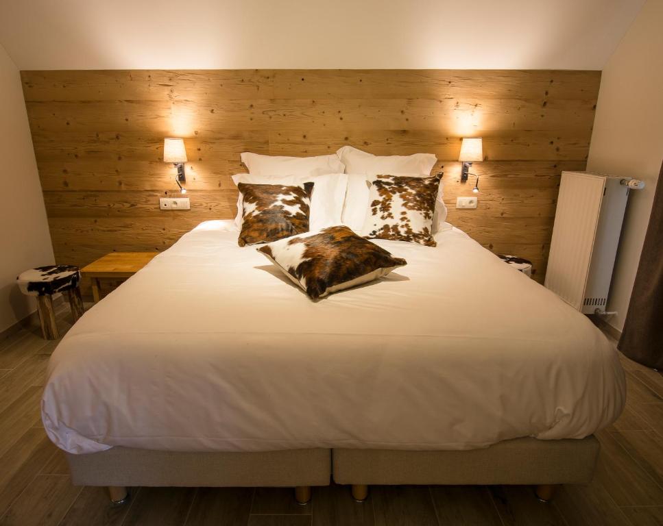 a bedroom with a large white bed with two pillows at Au Cheval Blanc in Waimes