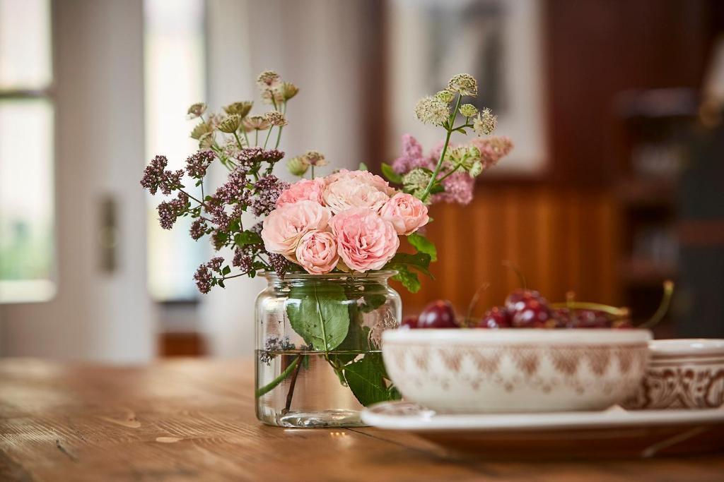 een glazen pot met roze bloemen naast een kom bij mein.lychen in Lychen
