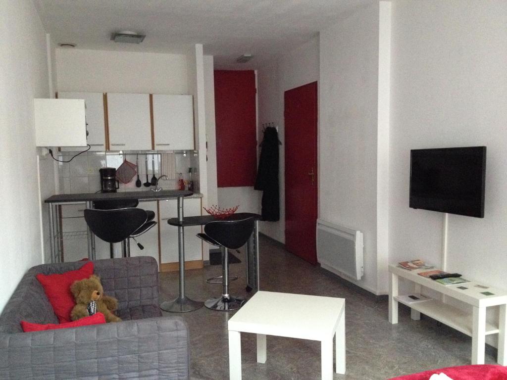 a living room with a couch and a kitchen with red walls at L'Acacia in Forbach