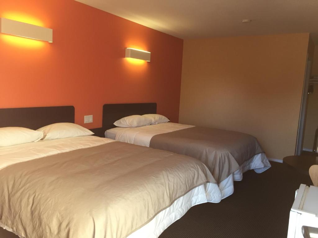 2 camas en una habitación de hotel con paredes de color naranja en Riverside Motel Cache Creek, en Cache Creek
