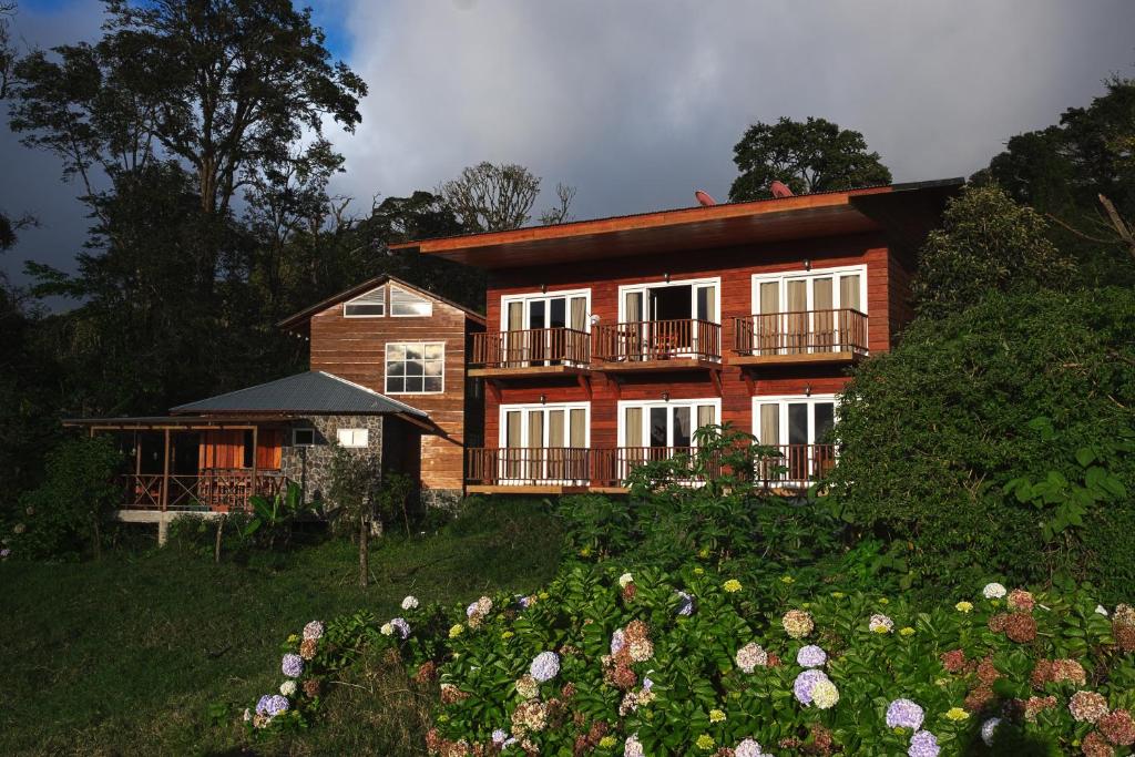 a house on a hill with flowers in front of it at Hotel Bosque Verde Lodge in Monteverde Costa Rica