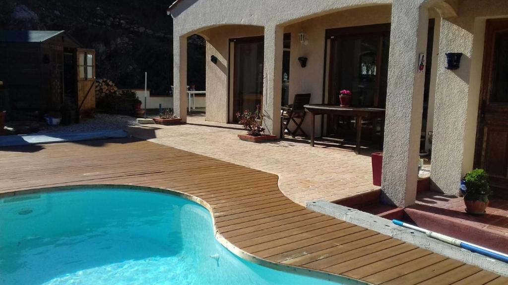 a swimming pool with a wooden deck next to a house at Les hauteurs de Collioure in Collioure