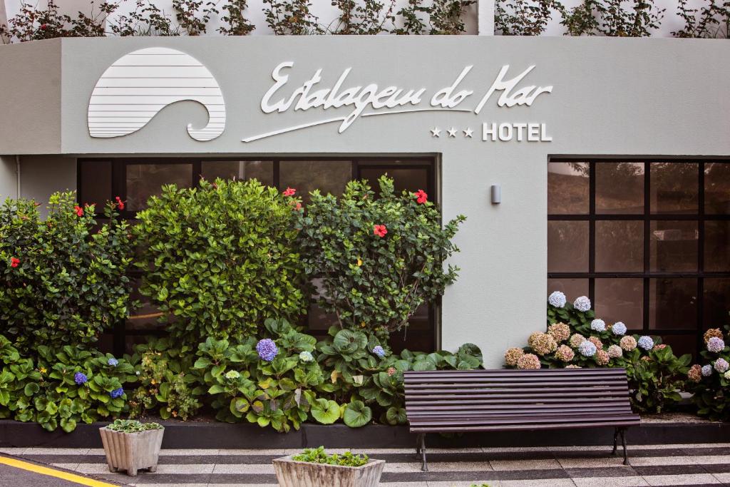 a hotel with a bench in front of a building at Estalagem do Mar in São Vicente