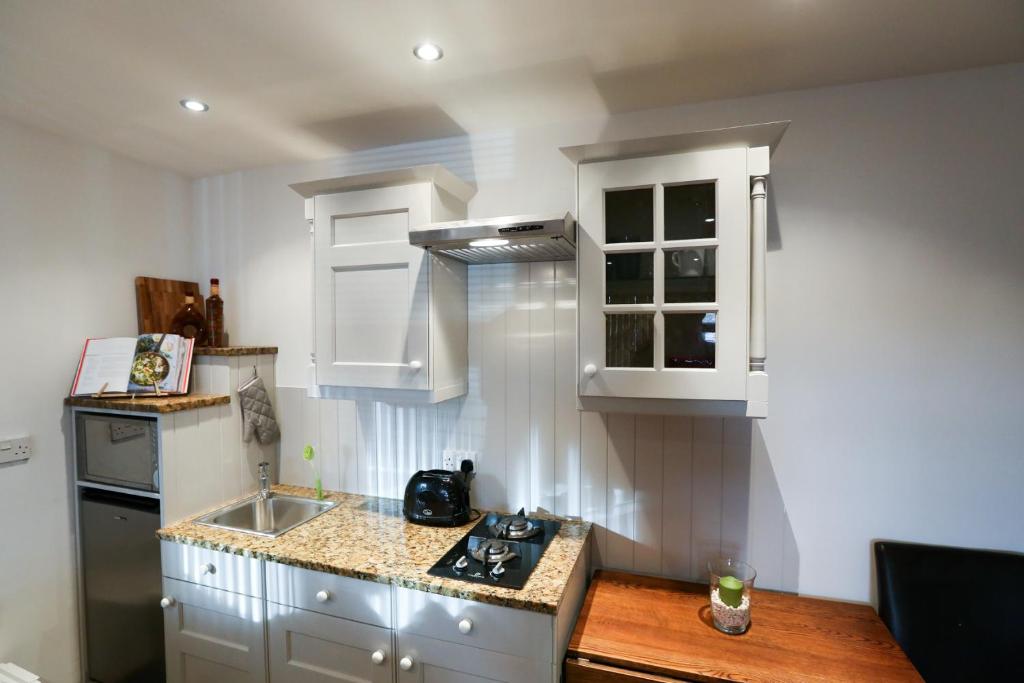 een kleine keuken met witte kasten en een wastafel bij Crackin View Holiday cottage in Hexham