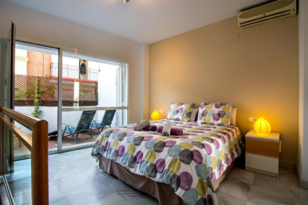 a bedroom with a bed and a large window at DescubreHome Sol Town Center Private Terrace in Seville