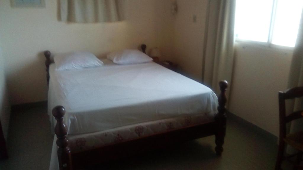 a bedroom with a bed with white sheets and a window at Hotel Chez Julot in Le Vauclin