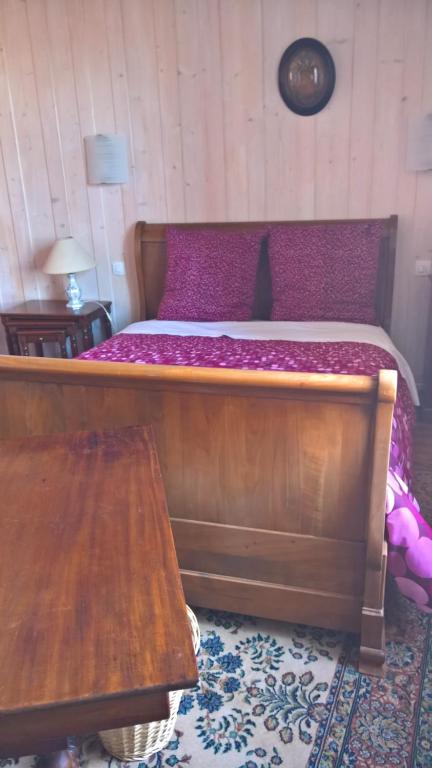 Schlafzimmer mit einem Holzbett und einem Holztisch in der Unterkunft Chambre d Hote 1873 in Frasne