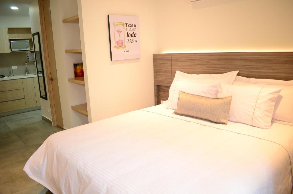 a bedroom with a large white bed with a wooden headboard at Antope - Apartaestudios in Cali