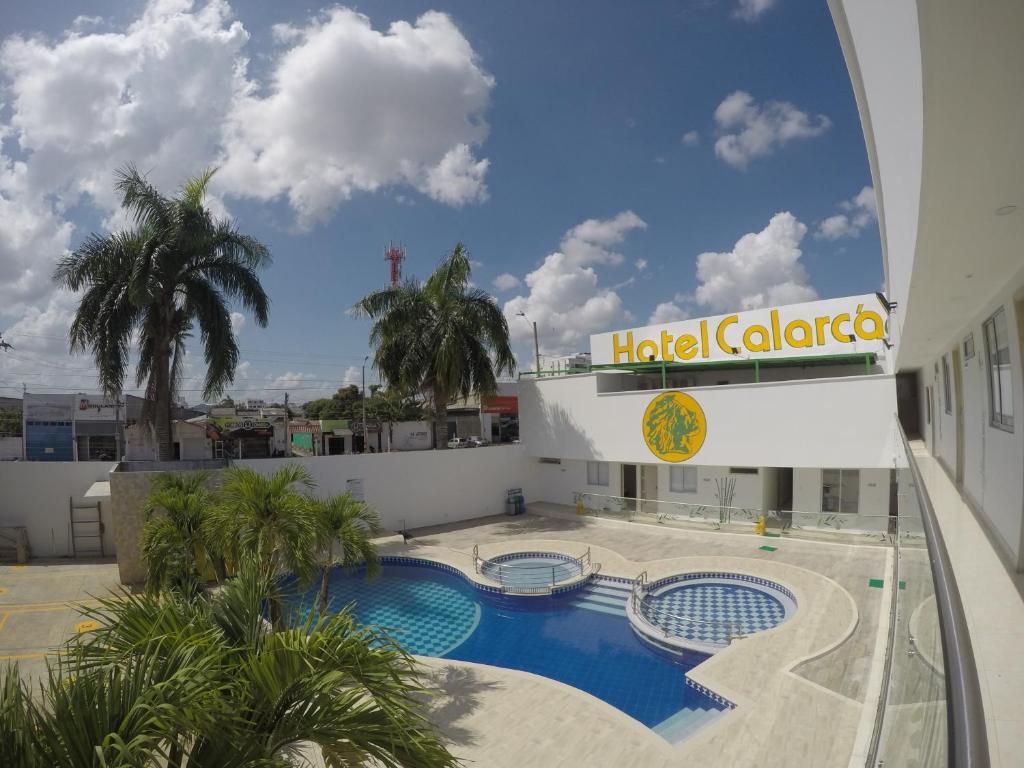 un hotel edificio gallardo con piscina y palmeras en Hotel Calarca Club, en Montería