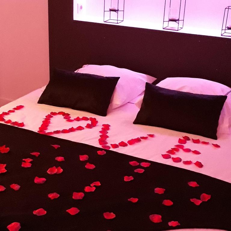 a bed covered in red hearts on a black blanket at La Pause Romantique in Dole