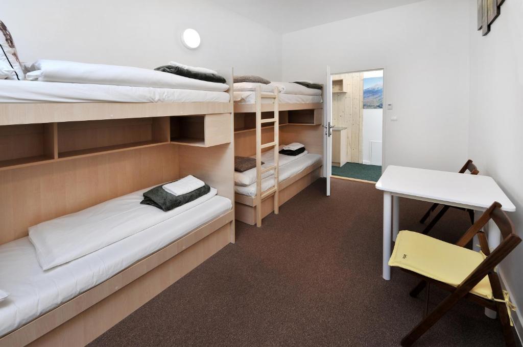 a room with bunk beds and a desk and a table at Bel Hostel in Tatranská Lomnica