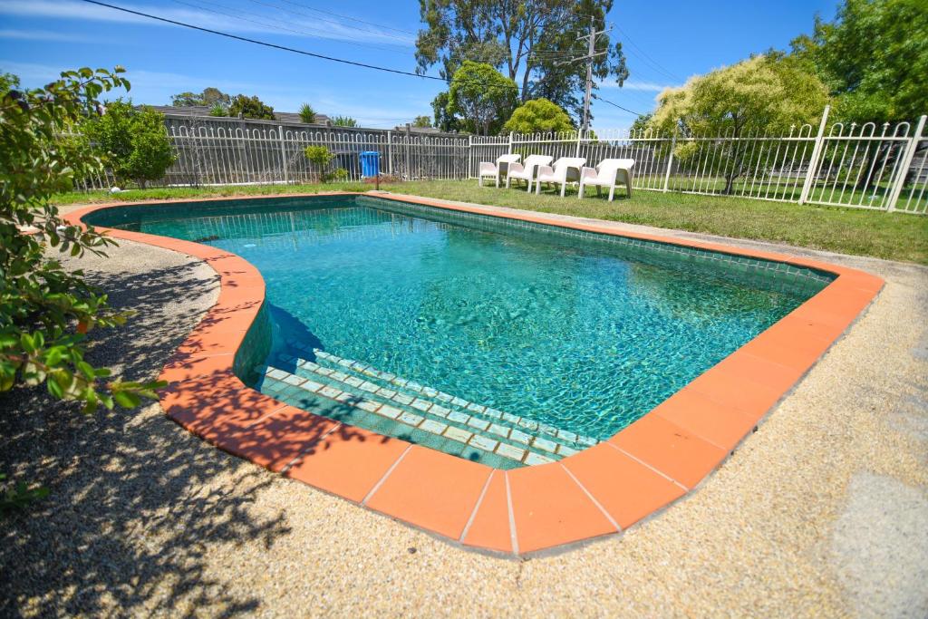 a swimming pool with an orange curb around it at Sandown Heritage Motel in Noble Park