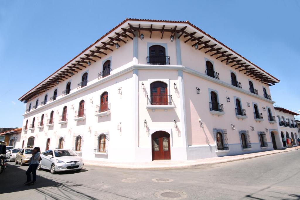 a white building with a woman standing in front of it at Hotel La Recolección in León