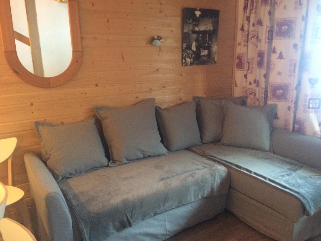 a couch in a room with a wooden wall at Duplex Apartment Right At The Ski Lift Tracks in Valmorel