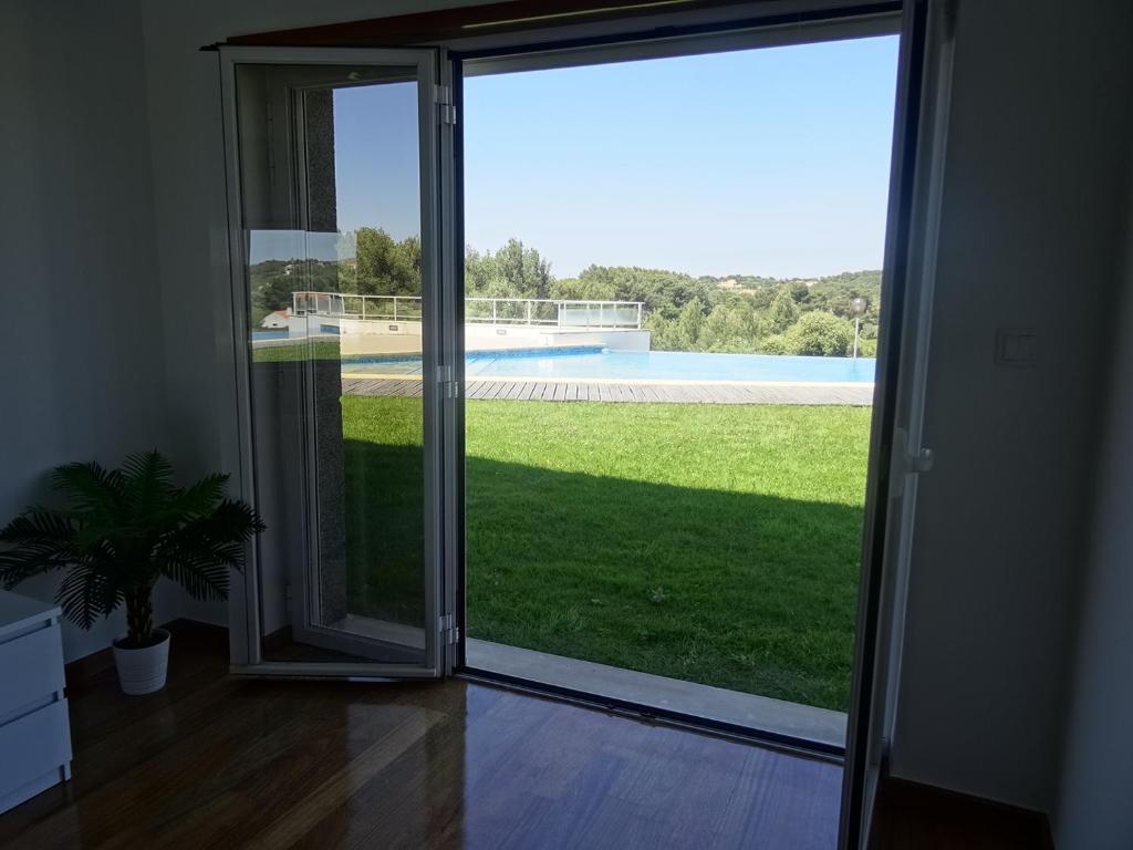 an open sliding glass door with a view of a yard at Condomínio jardim das oliveiras in Alcabideche