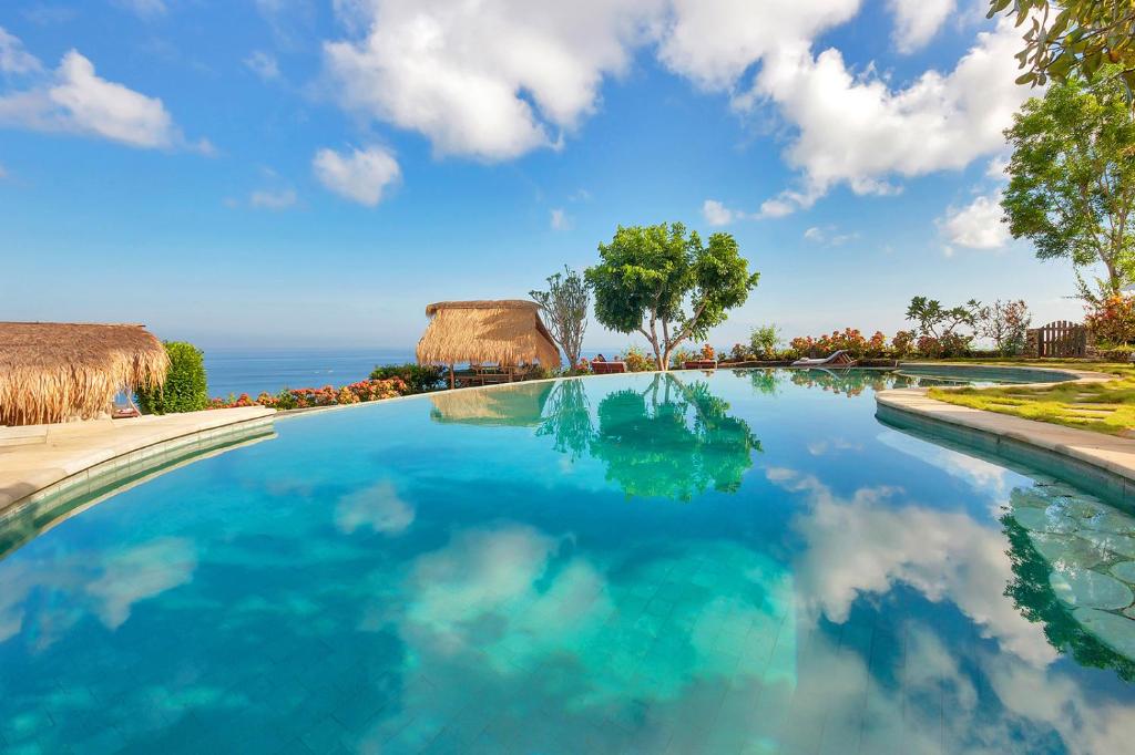 a swimming pool with a view of the ocean at Mu Bungalows in Uluwatu