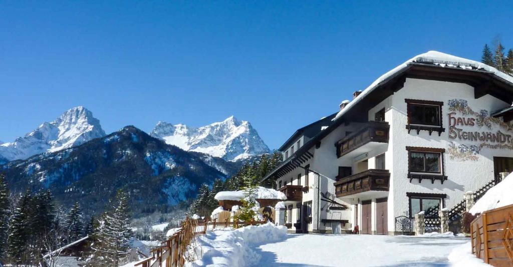 um edifício coberto de neve com montanhas ao fundo em Haus Steinwaendt em Hinterstoder