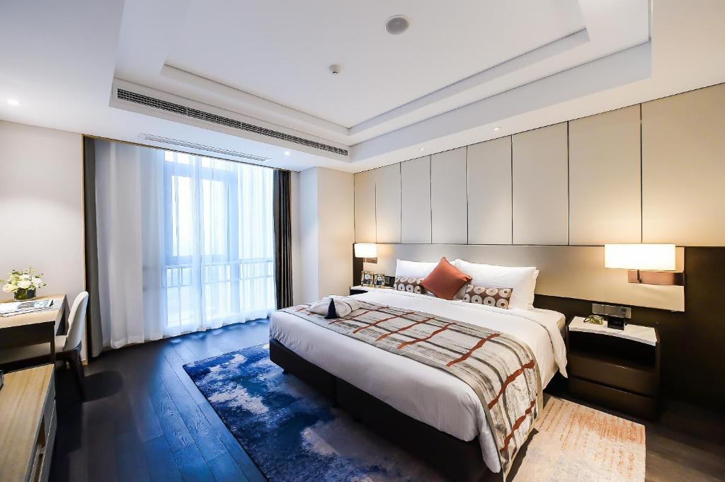 a hotel room with a large bed and a desk at Somerset Harmony City Wuxi in Wuxi