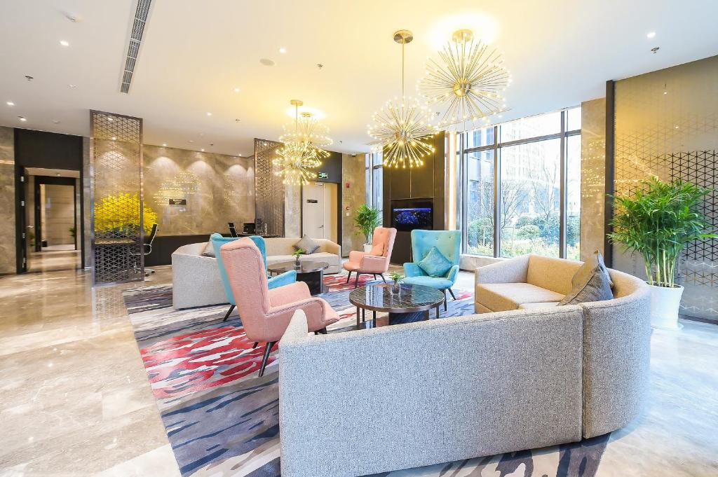 a lobby with a couch and chairs and a table at Somerset Harmony City Wuxi in Wuxi