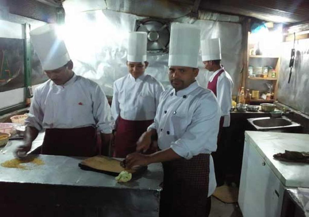 a group of chefs standing in a kitchen preparing food at Uttarakhand resort in Kausani