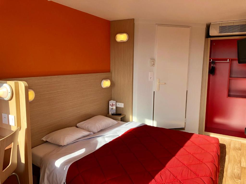 a bedroom with a bed and a lamp at Premiere Classe Perpignan Sud in Perpignan