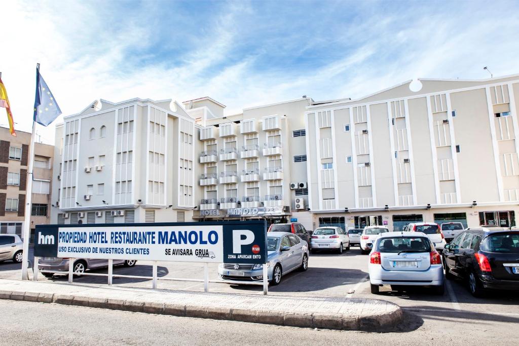 a parking lot with cars parked in front of a large building at Manolo in Cartagena