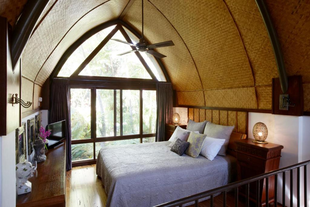 a bedroom with a bed and a large window at Garden Burees in Byron Bay