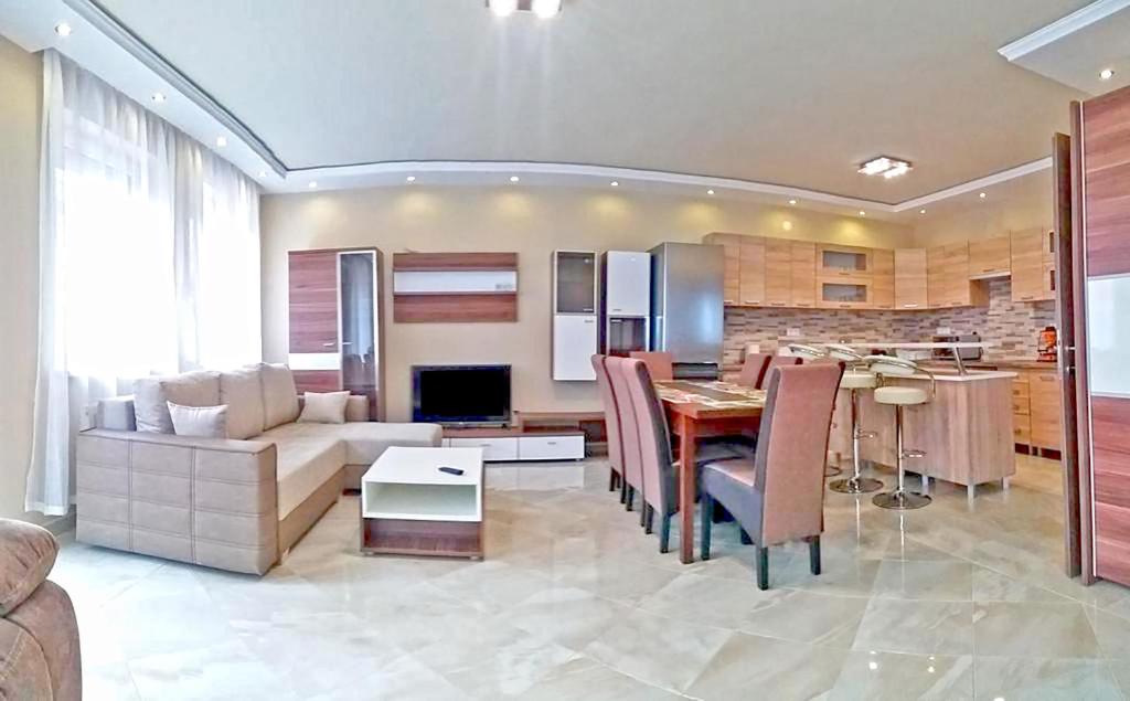 a living room with a kitchen and a dining room at Central-Aqua Apartman in Gyula