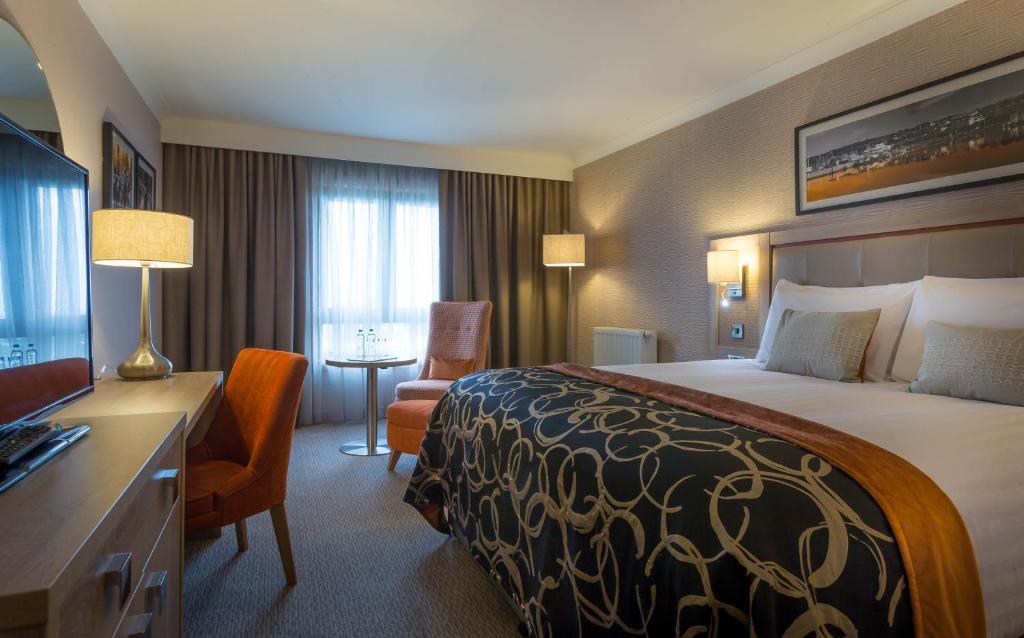 a hotel room with a large bed and a large window at Clayton Hotel, Manchester Airport in Hale