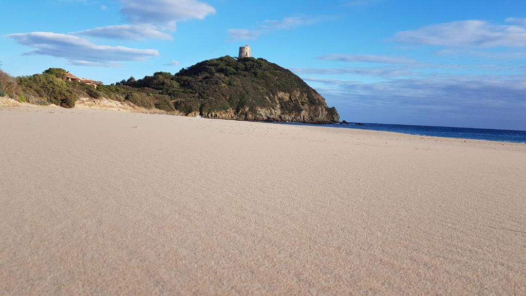 een strand met een vuurtoren in het midden van de oceaan bij villa sul mare a Chia in Domus de Maria