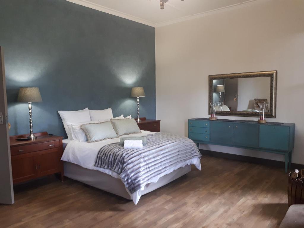 a bedroom with a bed with a blue dresser and a mirror at De Mist Graskop in Graskop