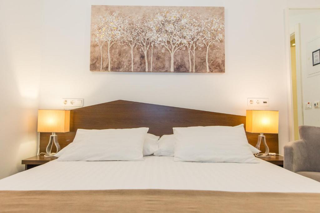 a bedroom with a white bed with two lamps at Villa Four Winds II in Dubrovnik