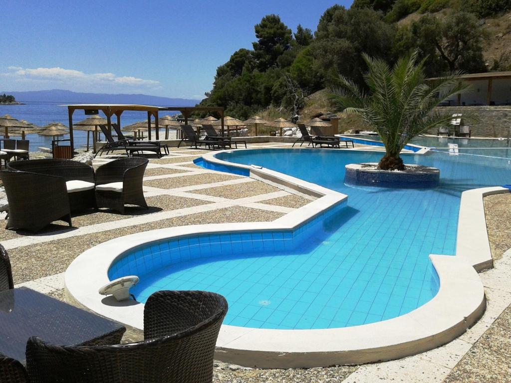 a blue swimming pool with chairs and a table at Blue Green Bay in Panormos Skopelos