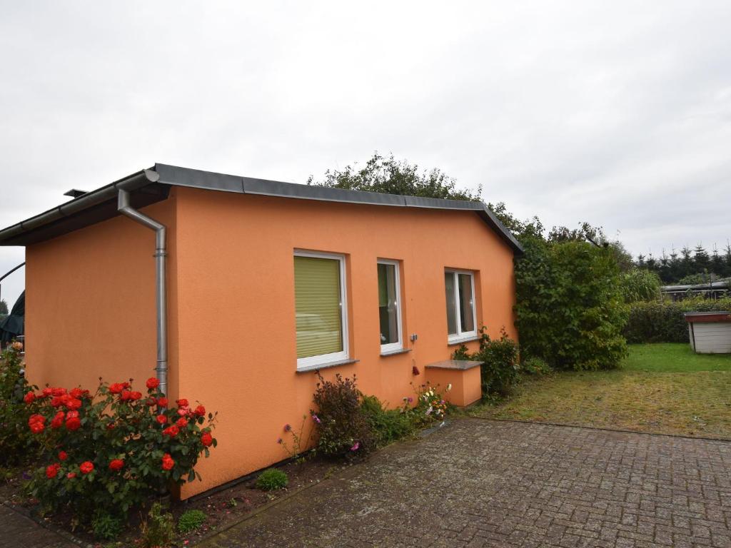 a small orange house with flowers in front of it at Quaint Bungalow in Reddelich near Baltic Sea Coast in Reddelich