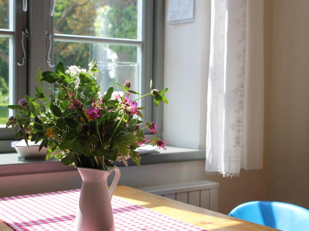 a vase of flowers sitting on a table with a window at Lush Apartment in Steffenshagen with Garden in Steffenshagen