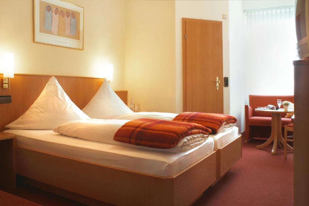 Una cama en una habitación de hotel con almohadas. en Hotel Rose Heidelberg inklusive Frühstück & Saunanutzung en Heidelberg
