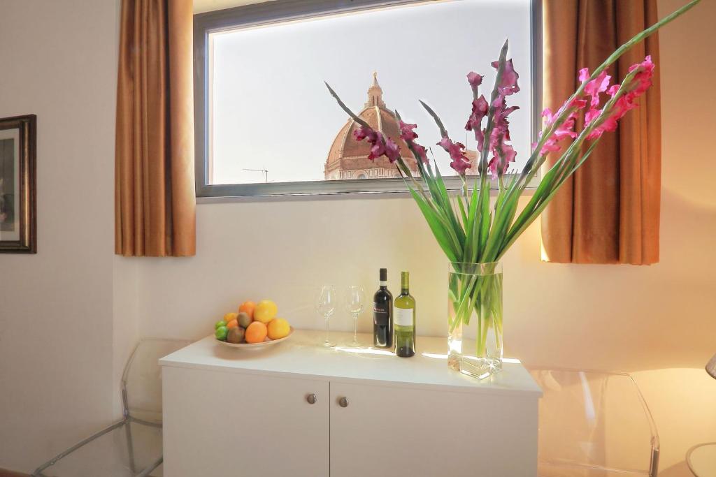 un vaso di fiori in cima a un mobile con bottiglie di vino di Relais Martinez Florence a Firenze