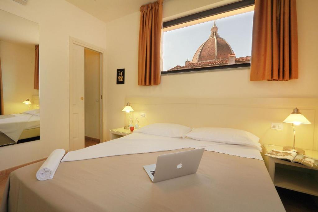 une chambre d'hôtel avec un lit et un ordinateur portable. dans l'établissement Relais Martinez Florence, à Florence