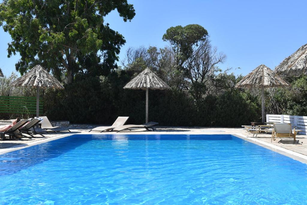 a swimming pool with chairs and umbrellas at Surfing Beach Village Paros in Santa Maria