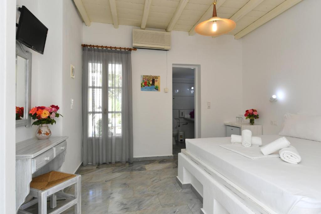 a white bedroom with a large bed and a television at Surfing Beach Village Paros in Santa Maria