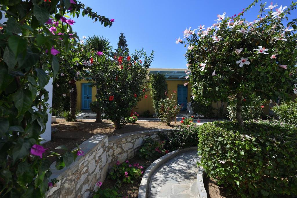a garden with flowers and trees and a building at Surfing Beach Village Paros in Santa Maria