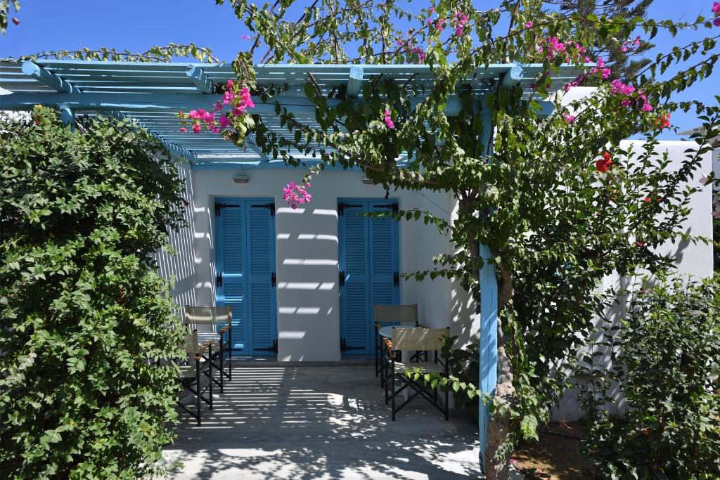 a pergola with blue doors and pink flowers at Surfing Beach Village Paros in Santa Maria