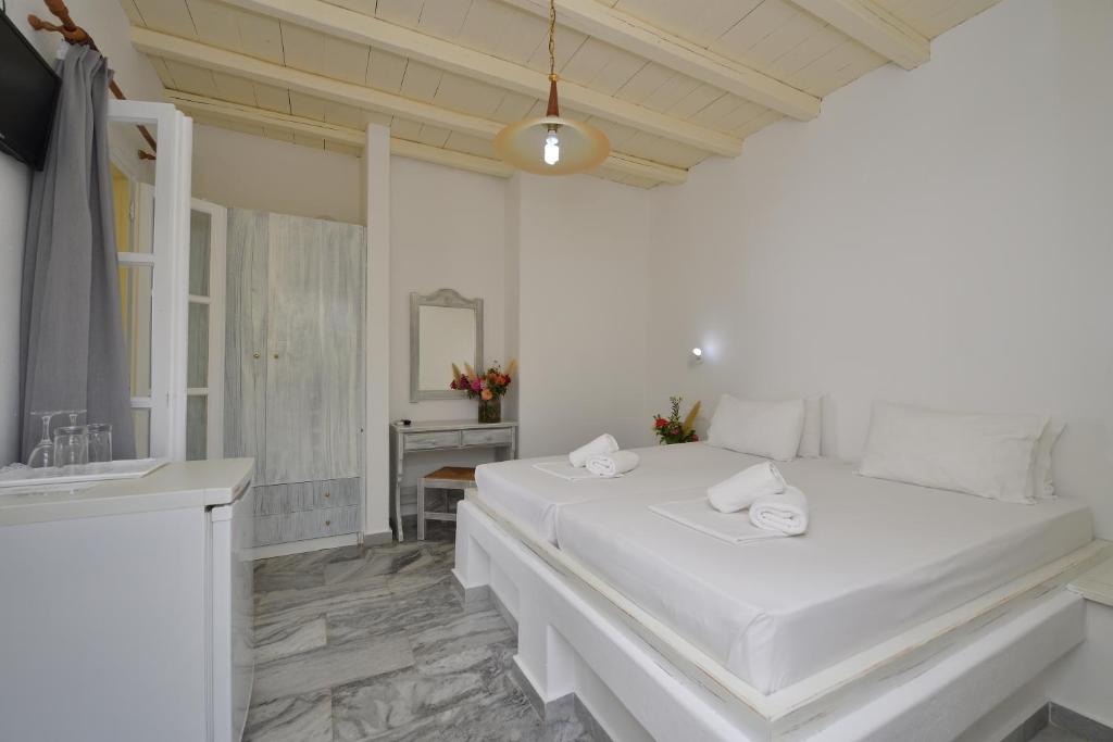 a white bedroom with a large bed and a sink at Surfing Beach Village Paros in Santa Maria