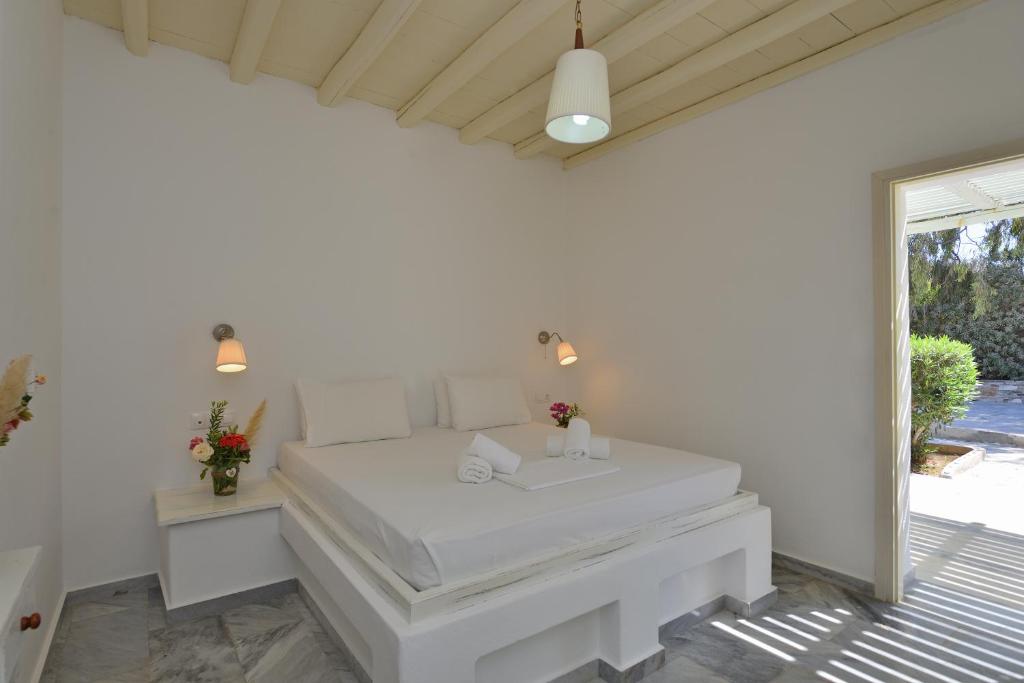 a white bedroom with a large bed and a window at Surfing Beach Village Paros in Santa Maria