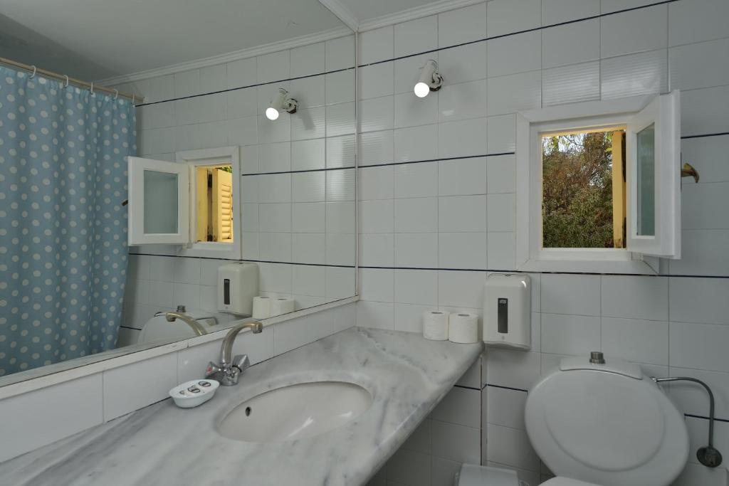a bathroom with a sink and a toilet and a mirror at Surfing Beach Village Paros in Santa Maria