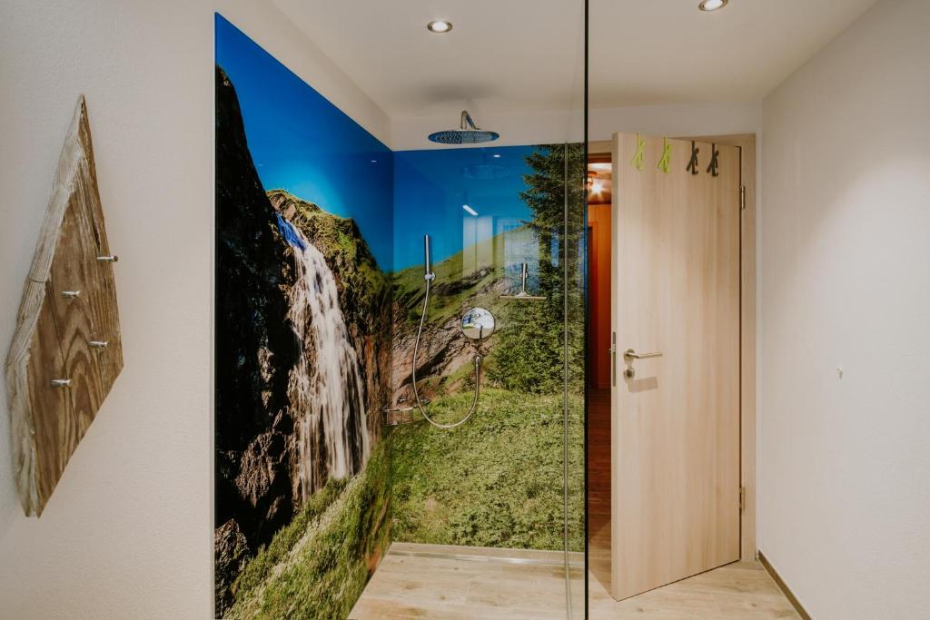 bagno con un dipinto a cascata sul muro di Chalet Aloa ad Adelboden