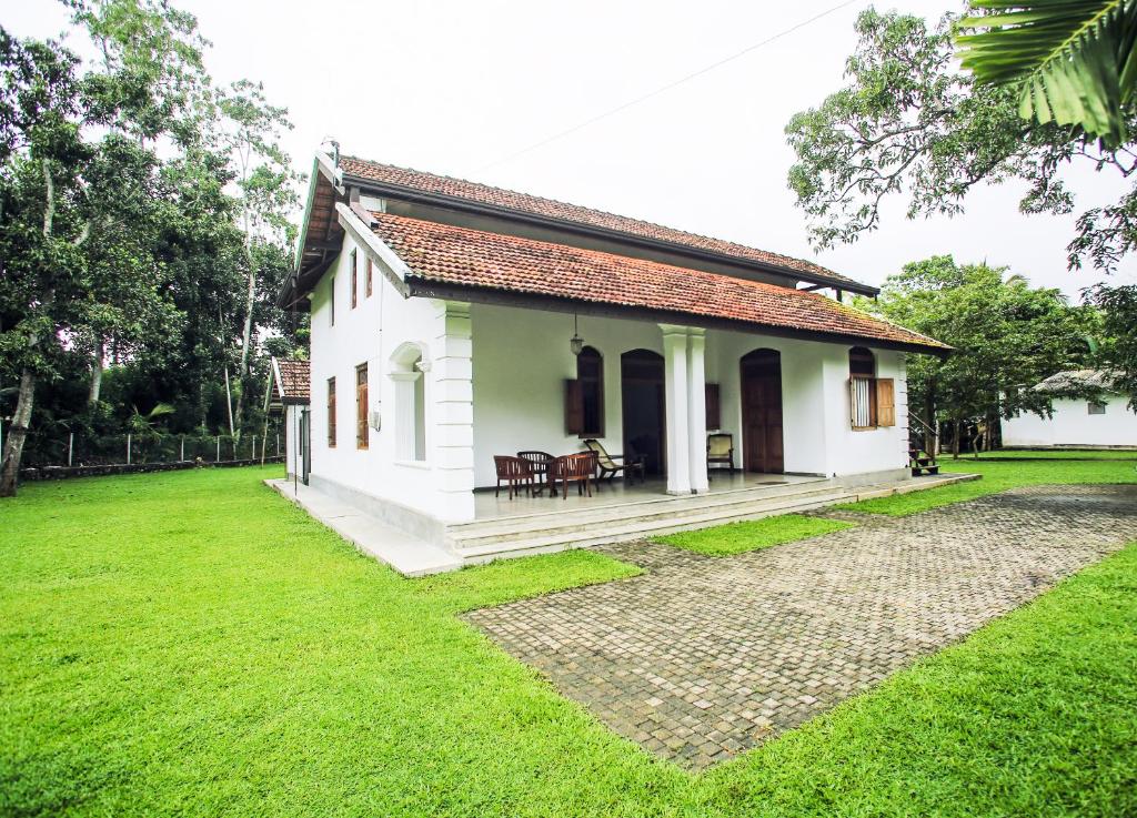 una pequeña casa blanca con un patio de césped en Villa Indrasiriya, en Ahangama