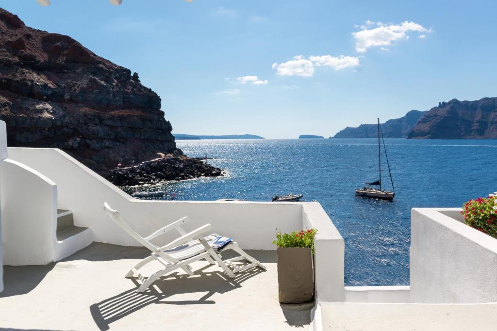 a pair of chairs sitting on a balcony overlooking the ocean at Amoudi Villas in Oia